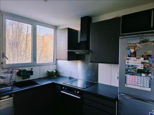 eine Küche mit schwarzen Schränken und einem Kühlschrank in der Unterkunft Locations de Chambres Proches de Paris à Massy in Massy