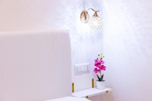 ein Badezimmer mit einem WC und einer Vase aus Blumen auf einem Regal in der Unterkunft Ginevra Luxury Taormina in Taormina