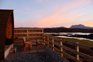 Een paar stoelen op een terras met een hek. bij Badcall Bay Retreat in Badcall