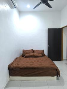 a bed in a room with a ceiling fan at Nani Homestay in Kampong Bukit Kuang