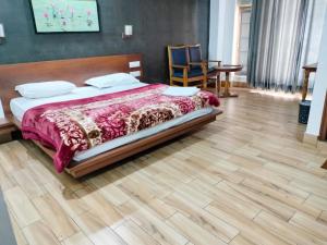 a bedroom with a bed and a wooden floor at Hotel Allseasons in Roorkee