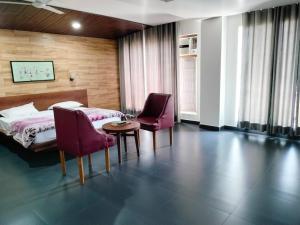 a bedroom with a bed and two chairs and a table at Hotel Allseasons in Roorkee
