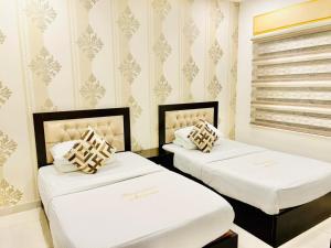Twee bedden in een kamer met witte muren en behang. bij Panorama Amman Hotel in Amman +19 foto's