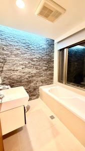 une salle de bain avec un lavabo et une baignoire et une fenêtre dans l'établissement Jiufen Breeze 九份惠風民宿ｌ6人包棟小屋, à Jiufen