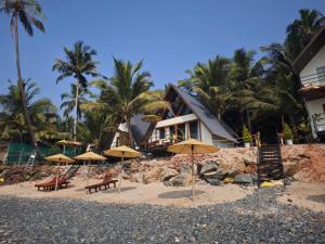 een resort met stoelen en parasols op een strand bij Colomb Beach Cottages in Patnem +38 foto's