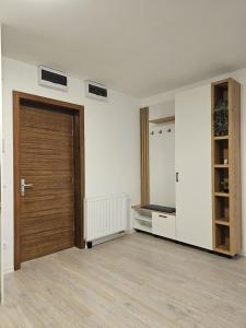 une chambre vide avec une porte en bois et des murs blancs dans l'établissement Luxury District - Panoramic View Urban Apartment, à Târgu-Mureş