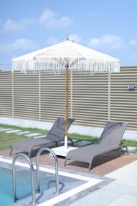 two lounge chairs and an umbrella next to a pool at Beloris Bungalov in Erenköy