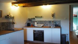 a kitchen with white cabinets and a stove top oven at La Vache Bleue in Saint-Pierre-de-Fursac
