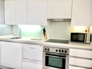 een witte keuken met een fornuis en een magnetron bij Panoramic Suites II By VALENCIAFLATS EU in Valencia