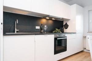 una cucina con armadietti bianchi e una parete nera di DAS GRÜNE NEST Münsterland Living a Drensteinfurt