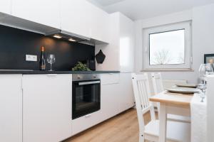 una cucina con mobili bianchi, un tavolo e una finestra di DAS GRÜNE NEST Münsterland Living a Drensteinfurt Altre 32 foto