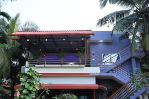 a building with a staircase and palm trees at VAISHVI Homestay in Kāsarkod