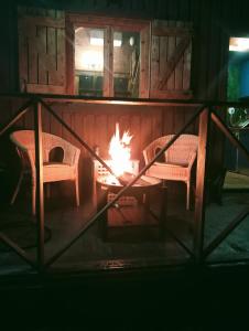 zwei Stühle und ein Feuer im Kamin in der Unterkunft La Cabaña del Paito in Guillena