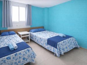 twee bedden in een kamer met blauwe muren bij San Jordi Tossa de Mar in Tossa de Mar +28 foto's