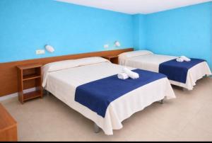 twee bedden in een kamer met blauwe muren bij San Jordi Tossa de Mar in Tossa de Mar