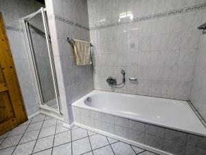 a bathroom with a white tub and a shower at Geigerhof Bad Heilbrunn in Bad Heilbrunn +8 photos