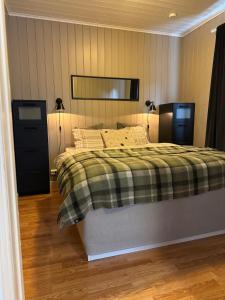 een slaapkamer met een bed met een groene deken en 2 lampen bij Leilighet Ski in/out, golf in Vradal