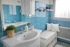 een blauw betegelde badkamer met een wastafel en een raam bij Haus am Bodensee in Fußach +19 foto's