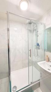 une douche avec une porte en verre dans une salle de bain dans l'établissement Modern 1 bed super fast WiFi, à Brentford