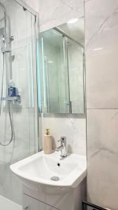 un bagno bianco con lavandino e doccia di Modern 1 bed super fast WiFi a Brentford