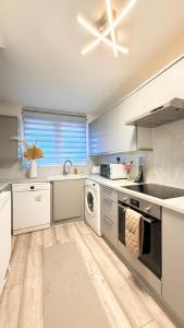 una cucina con mobili bianchi, lavatrice e asciugatrice di Modern 1 bed super fast WiFi a Brentford