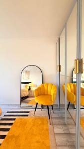 un salon avec une chaise jaune et un miroir dans l'établissement Modern 1 bed super fast WiFi, à Brentford