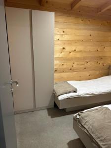 a bedroom with two beds and a wooden wall at Suncatcher Djurdjevic Apartmani in Banja Luka