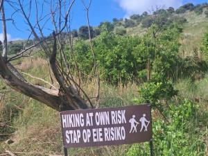 een bord met de tekst 'wandelen op eigen risico' zit hier omhoog opkomend bij Mount Everest Guest Farm in Harrismith