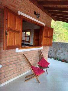 due sedie appoggiate su un patio di fronte a un muro di mattoni di Chalés Maktub a Camanducaia