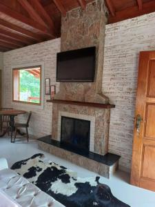 un soggiorno con camino e TV su un muro di mattoni di Chalés Maktub a Camanducaia