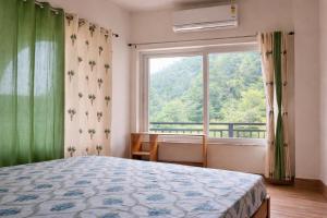 a bedroom with a bed and a large window at Om Homestay in Rishīkesh