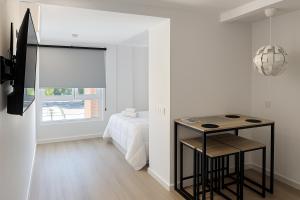 a white bedroom with a bed and a table at Prime Suites Valencia in Valencia