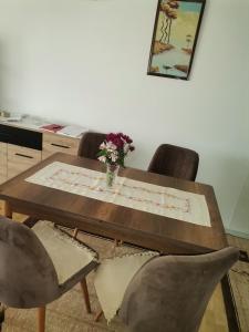 un tavolo in legno con sedie e un vaso di fiori sopra di Mala Sirena a Pirot