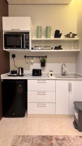 a kitchen with white cabinets and a microwave at Hanay Studio in Al Khobar