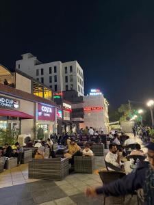 eine Gruppe von Menschen, die nachts in einer Stadt auf Stühlen sitzen in der Unterkunft Rose Palace Hotel, Liberty in Lahore