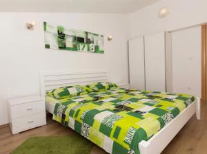 a bedroom with a bed with a yellow and green comforter at Apartmani Attila in Trogir +18 photos