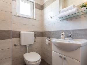 a white bathroom with a toilet and a sink at Apartmani Attila in Trogir