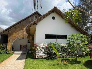 a white house with an archway in a yard at MANOLO Beach Resort in Uroa +14 photos