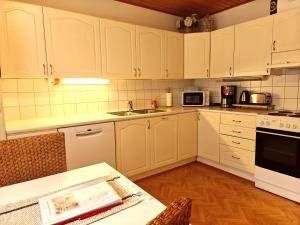 - une cuisine avec des placards blancs, un évier et une table dans l'établissement Peaceful house for relaxing, à Oulu