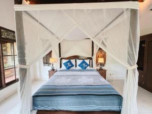 een slaapkamer met een hemelbed met blauwe kussens bij Rumah Kelinci in Ubud +227 foto's