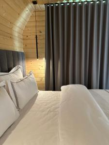 a bed with white sheets and pillows in a room at Hotel McPietroasa in Haleş