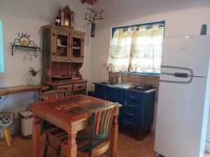 a kitchen with a wooden table and a refrigerator at Sopro da Serra Chalé Papagaio in Gonçalves
