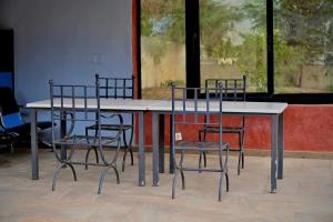 a table with four chairs and a table and a window at Hotel le Mbosse in Niaga