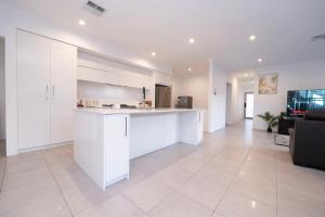 a kitchen with white cabinets and a living room at Henley Brook - Finest in Henley Brook +39 photos