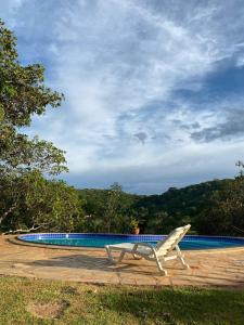 una sedia bianca seduta accanto alla piscina di Casa Das Flores Piri a Pirenópolis