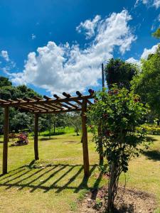 un pergolato di legno in un parco con un cespuglio di Casa Das Flores Piri a Pirenópolis