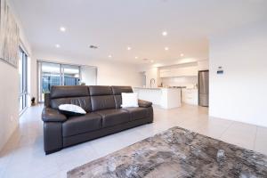 a living room with a leather couch and a kitchen at Henley Brook - Finest in Henley Brook