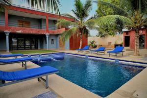 a swimming pool with blue lounge chairs in front of a building at Hotel le Mbosse in Niaga
