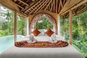 een bed in een kamer met een groot raam bij Umawana Villas in Tegalalang
