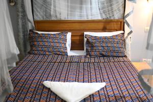two beds with pillows and a headboard in a bedroom at Hotel le Mbosse in Niaga +1 photo